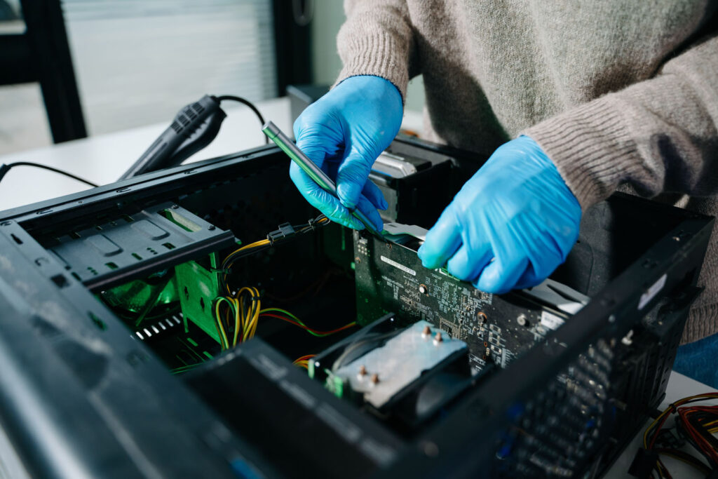 computer technician in gloves safely repairing desktop hardware.